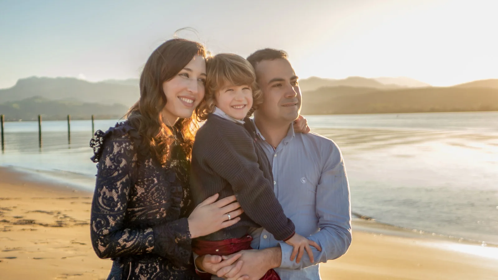 Familia abrazada en la playa al atardecer